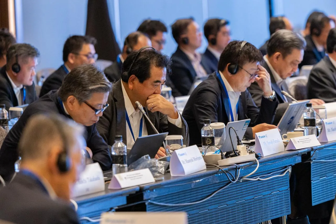 Conference delegates seated with headsets and table microphones