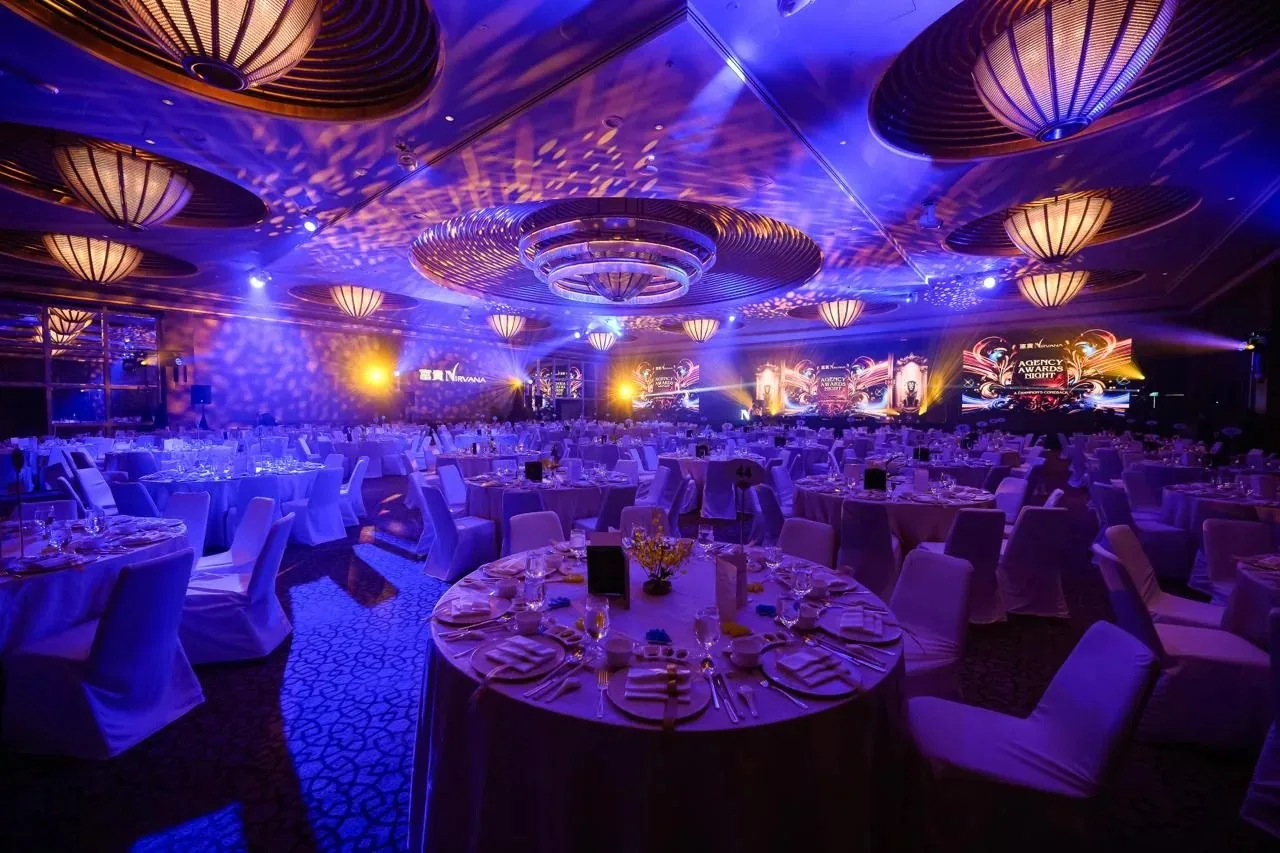 Ballroom set for a corporate awards celebration with stage lighting and banquet seating
